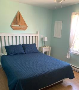 a blue bedroom with a bed with a blue comforter at Whispering Waves Cottages in Shelburne