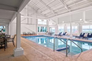 een groot binnenzwembad met stoelen en een tafel bij Delta Hotels by Marriott Milwaukee Northwest in Menomonee Falls