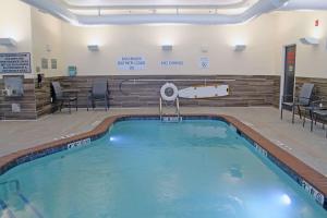 a swimming pool in a gym with chairs and tables at Fairfield by Marriott Inn & Suites St Louis South in Saint Louis