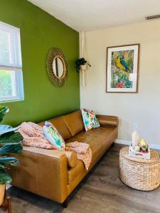 a brown couch in a room with a green wall at Tropical Casita in Tampa near airport and Raymond James stadium in Tampa