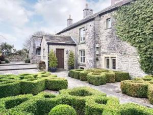 an old stone house with bushes in front of it at Sweet Knoll Farm in Peak Forest