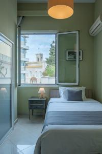 a bedroom with a bed and a large window at Kimon Hotel Athens in Athens