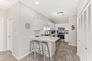a kitchen with white cabinets and a counter with stools at GulfShores BeachCondo - Pool - FreeParking - SummerTime! - Little Lagoon in Gulf Shores