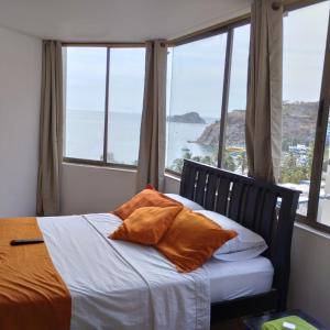 a bed with orange pillows in a room with windows at CyM Arriendos 904 in Santa Marta