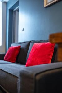 a black couch with two red pillows on it at Escapade Place 11 - Appartement A2 Dinan centre in Dinan