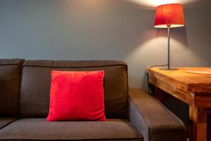 a red pillow sitting on a couch next to a lamp at Escapade Place 11 - Appartement A2 Dinan centre in Dinan