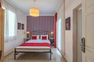 - une chambre avec un lit et une couverture rouge dans l'établissement Kimon Hotel Athens, à Athènes