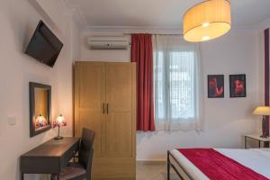 a bedroom with a bed and a desk and a window at Kimon Hotel Athens in Athens