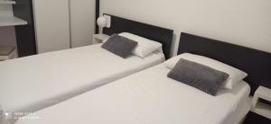2 camas en un dormitorio con sábanas y almohadas blancas en Neno, en Primošten