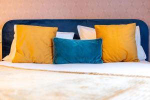 een bed met gele en blauwe kussens erop bij Escapade Place 11 N3- Studio Dinan centre in Dinan