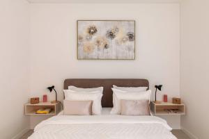 een slaapkamer met een bed met witte lakens en roze kussens bij Central Superior Suites - Free Parking in Lugano