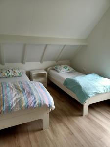 twee bedden in een kamer met witte muren en houten vloeren bij Vakantiehuis Mastdreef in Breda