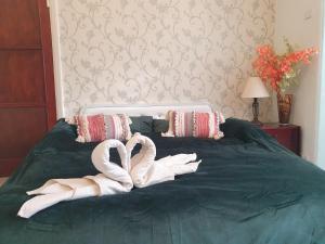 Dos cisnes de toalla sentados en una cama verde en Beautiful Double En-suite Room, separate entrance, Ilford, Central line Gants Hill, free parking, en Ilford