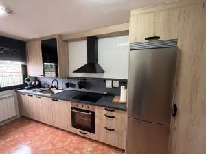 uma cozinha com um frigorífico de aço inoxidável e um fogão em Apartamento Ahola II em Ponferrada