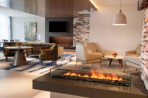 a lobby with a fireplace and chairs and tables at Fairfield by Marriott Edmonton International Airport in Edmonton