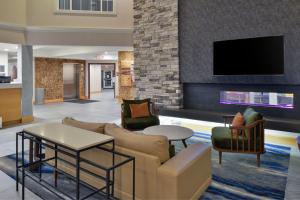 a lobby with a couch and chairs and a tv at Fairfield Inn & Suites Goshen Middletown in Goshen