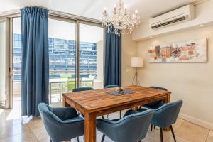a dining room with a wooden table and blue chairs at V&A Waterfront Luxury Apartments from McStay in Cape Town