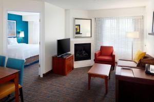 アース・シティにあるResidence Inn Saint Louis Airport / Earth Cityのベッドとリビングルームが備わるホテルルームです。