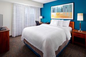 una habitación de hotel con una cama grande y paredes azules en Residence Inn Saint Louis Airport / Earth City, en Earth City