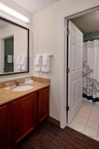 a bathroom with a sink and a mirror and a shower at Residence Inn Saint Louis Airport / Earth City in Earth City