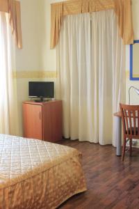 Schlafzimmer mit einem Bett, einem TV und Vorhängen in der Unterkunft Hotel Bellevue in Genua
