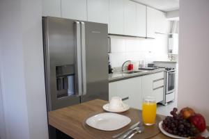 a kitchen with a refrigerator and a table with a plate of fruit at Atlântida Green Square - 601B in Capão da Canoa
