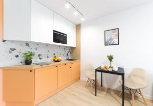 Apartamenty Meiera في كراكوف: مطبخ مع خزائن برتقال وطاولة سوداء