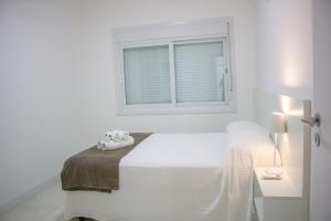a white bedroom with a bed and a window at Atlântida Green Square - 601B in Capão da Canoa +25 photos
