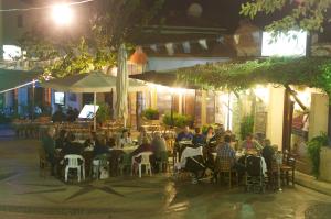 a group of people sitting at tables in a restaurant at night at Hylatio Tourist Village in Pissouri
