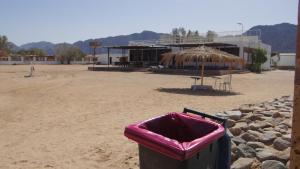a trash can in front of a building with an umbrella at OASIS Resort in Nuweiba‘ el Muzeinah