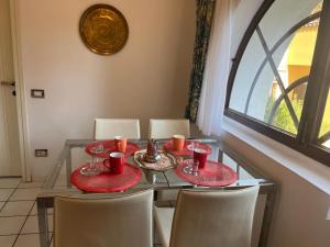 een glazen tafel met rode borden en bekers erop bij Villa Maria Callas Sirmione in Sirmione