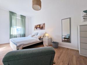 een slaapkamer met een bed, een spiegel en een bank bij HappySide - Sm00th - Landhaustil - WLAN - Nespresso in Leipzig