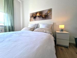 ein weißes Schlafzimmer mit einem weißen Bett und einer Lampe in der Unterkunft HappySide - Sm00th - Landhaustil - WLAN - Nespresso in Leipzig