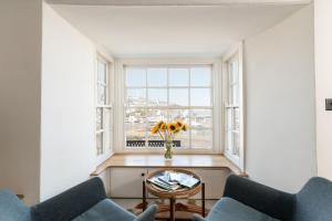 sala de estar con 2 sillas, mesa y ventana en The Sail House, en Brixham