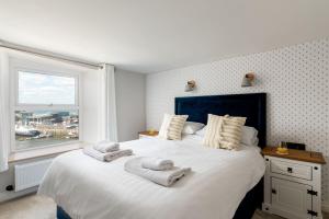 1 dormitorio con 1 cama blanca grande y toallas. en The Sail House, en Brixham