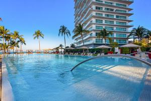 a large swimming pool next to a tall building at Seize The Sun, 1-1505 in Puerto Vallarta