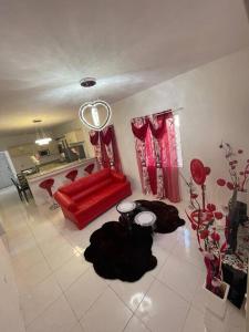 a living room with a red couch and red curtains at Mount Royal Estate Cozy Comfort in Portmore