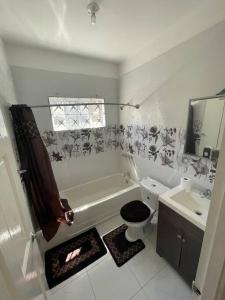 a bathroom with a tub and a toilet and a sink at Mount Royal Estate Cozy Comfort in Portmore