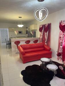 a living room with a red couch and a kitchen at Mount Royal Estate Cozy Comfort in Portmore