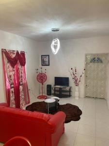 a living room with a red couch and a television at Mount Royal Estate Cozy Comfort in Portmore
