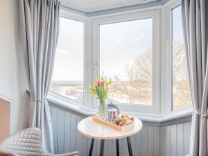 a table with a vase of flowers and a window at Harbour View House in Girvan