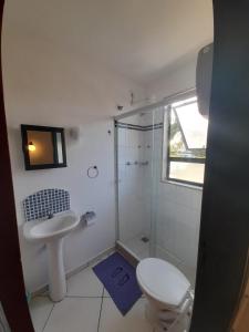La salle de bains est pourvue de toilettes, d'un lavabo et d'une douche. dans l'établissement Arraial Flats, à Arraial do Cabo