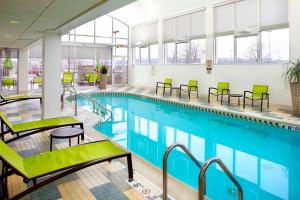 a swimming pool with green chairs in a building at SpringHill Suites by Marriott Chicago Waukegan/Gurnee in Waukegan