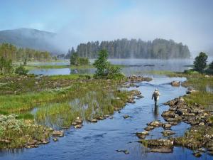 a man is walking through a river with a rod at Apartment Havsdalshovda - HLD101 by Interhome in Geilo