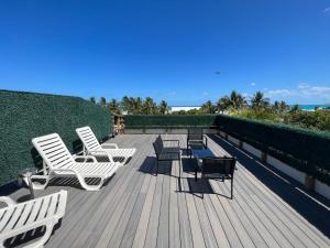 una terraza con sillas blancas, una mesa y un sillón en SOBE suites in Miami Beach en Miami Beach