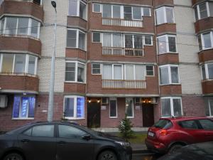 two cars parked in front of a brick building at Alex Hotel on Dybenko in Saint Petersburg