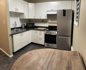 cocina con armarios blancos y nevera de acero inoxidable en Cozy Furnished Apartment, en Fort Simpson