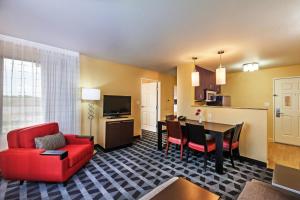 a living room with a red couch and a kitchen at TownePlace Suites by Marriott Tulsa Broken Arrow in Broken Arrow