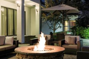 a fire pit in a patio with chairs and an umbrella at Courtyard Cincinnati Blue Ash in Blue Ash