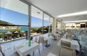 restauracja z białymi stołami i krzesłami oraz balkonem w obiekcie Villetta Relax Pugnochiuso w mieście Vieste